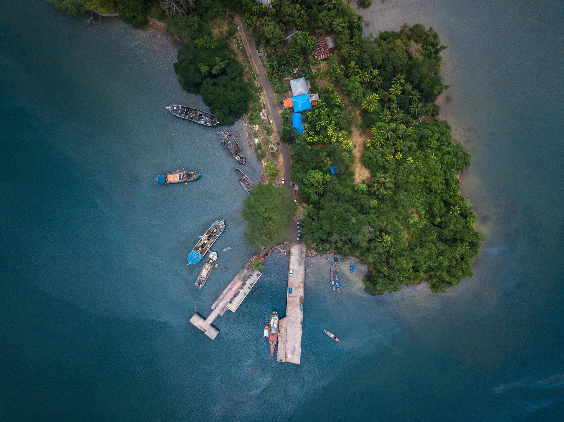 An aerial view of a green Andaman island, its jetty and surrounding sea